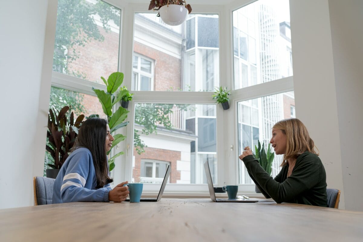 Photo by airfocus woman in black long sleeve shirt sitting beside woman in blue long sleeve shirt