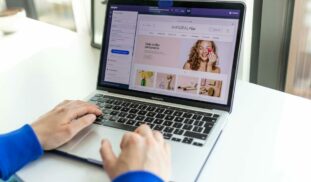 Hands typing on a laptop with an e-commerce website open, showcasing online shopping.