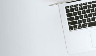 Aerial view of a sleek laptop keyboard on a clean, white surface, ideal for tech backgrounds.