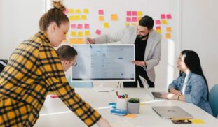man standing behind flat screen computer monitor