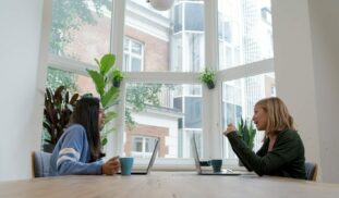 woman in black long sleeve shirt sitting beside woman in blue long sleeve shirt