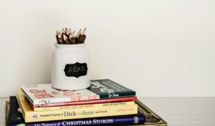 white ceramic pencil organizer on top of stack of books