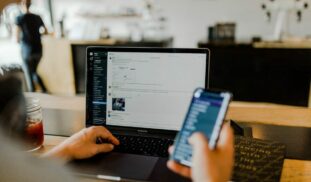 person using phone and laptop