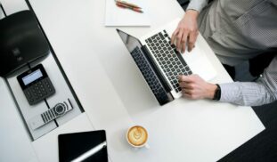person using laptop on white wooden table