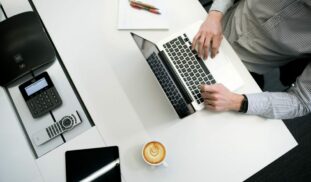 person using laptop on white wooden table