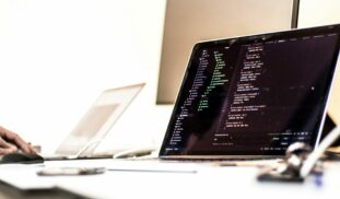 black laptop computer turned-on displaying source code on table